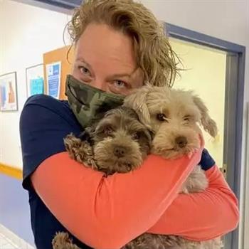 person cuddling two dogs